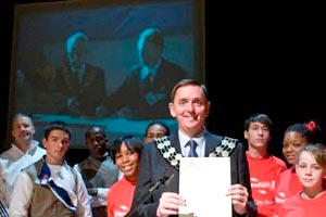 Mayor of Newham and children on stage with projection screen in background